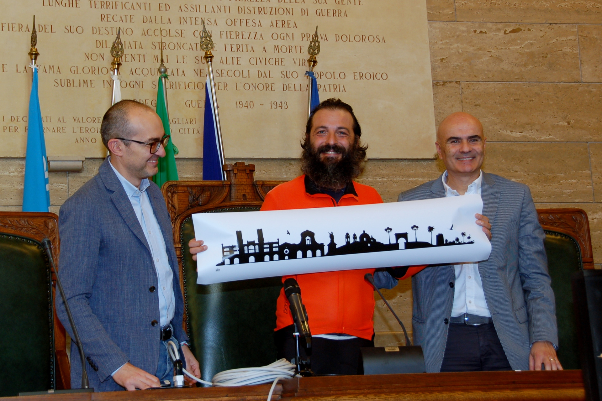 Il sindaco Paolo Truzzu e l'assessore  Sorgia consegnano la skyline di Cagliari a Sebastiano Dessanay